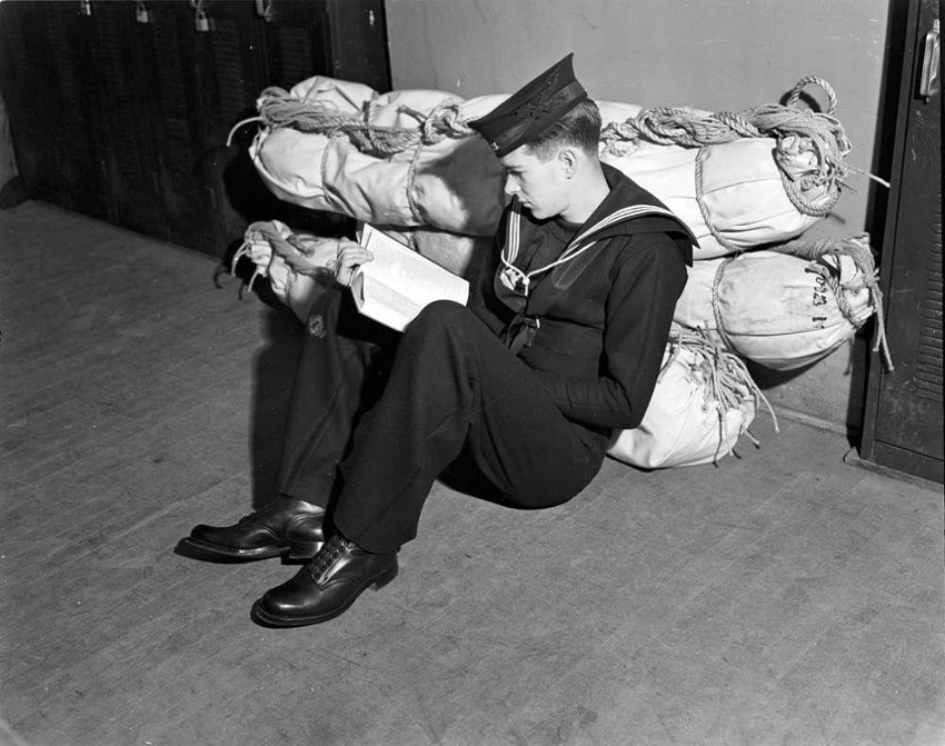 Young man in military uniform sits down writing